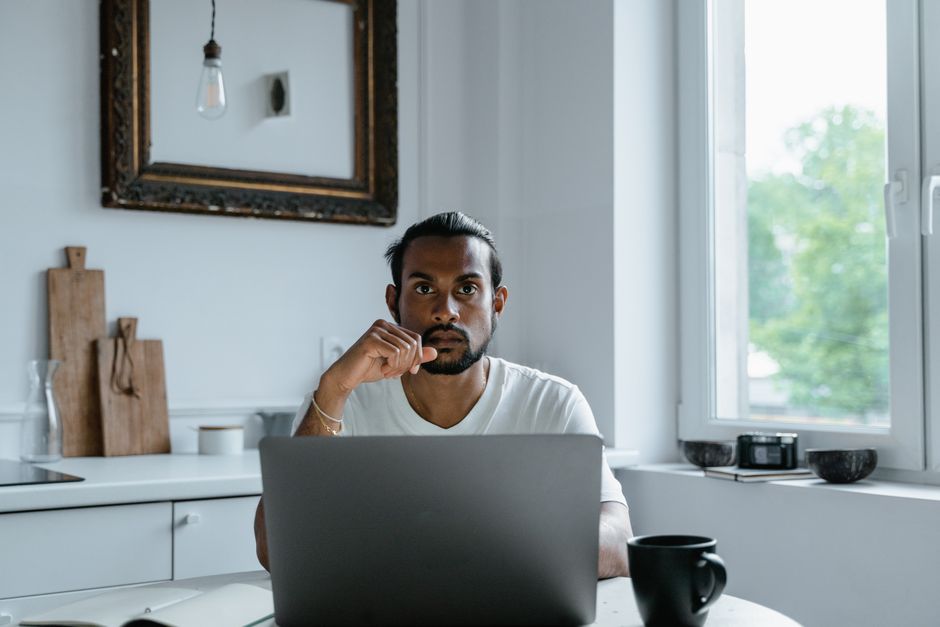 Person thinking at a laptop at home