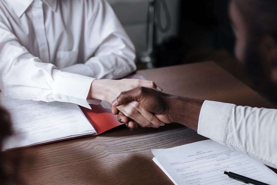 Two people shaking hands over a desk