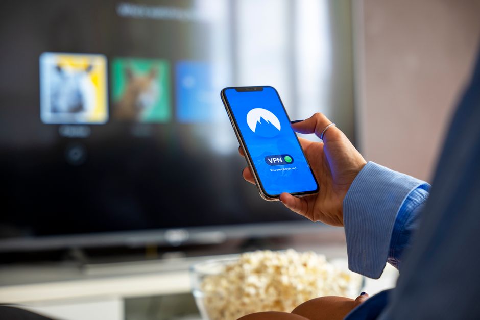 Viewer holding a remote in front of a television showing a streaming app